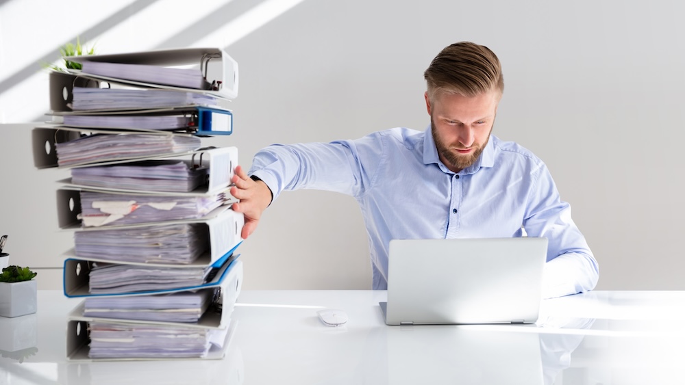 Businessperson Pushing Paper Documents Away And Working With Digital Documents On Computer Instead. Digital transformation, green IT concept.